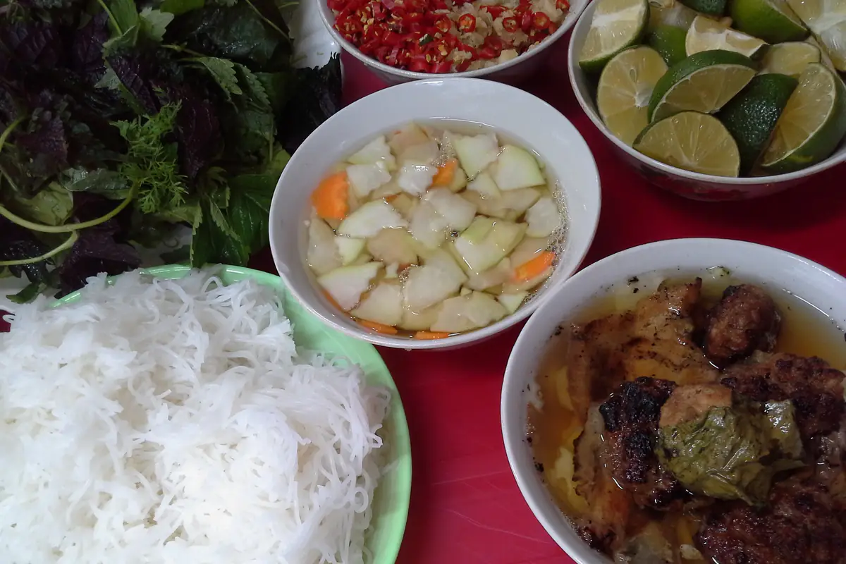 Một suất bún chả ở phố Hàng Mành, Hà Nội: bát nước chấm có đu đủ xanh và cà rốt thái miếng, bát chả miếng, chả viên và chả cuốn lá lốt, đĩa bún, rau sống, chanh và ớt, tháng 4/2016