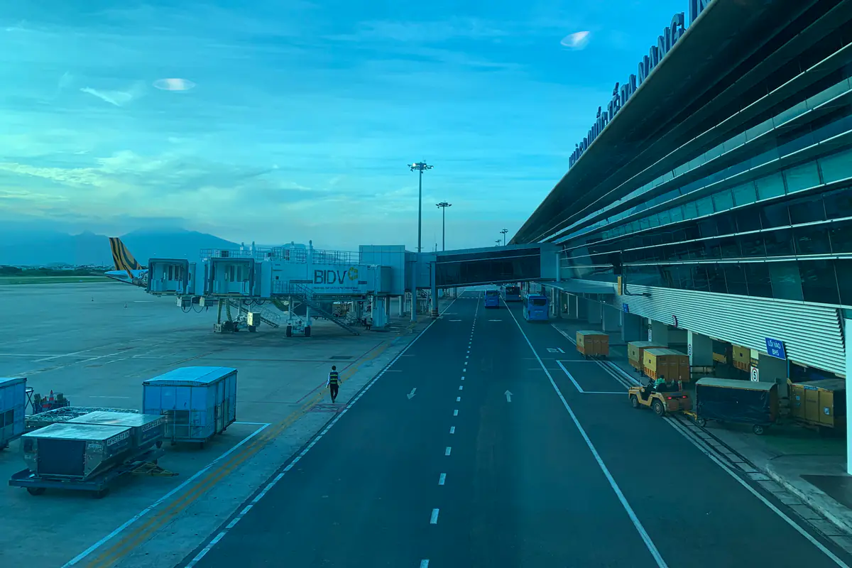 The glass front of Da Nang airport's international terminal seen from the apron in early morning, with planes at the jet bridges