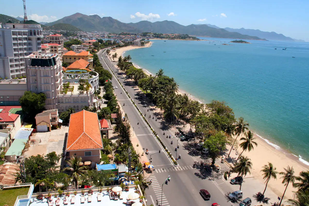 Đường Trần Phú nhìn từ trên cao, chạy song song bãi biển cong dài, hàng dừa và vỉa hè ven cát, núi phía xa, tháng 7/2007