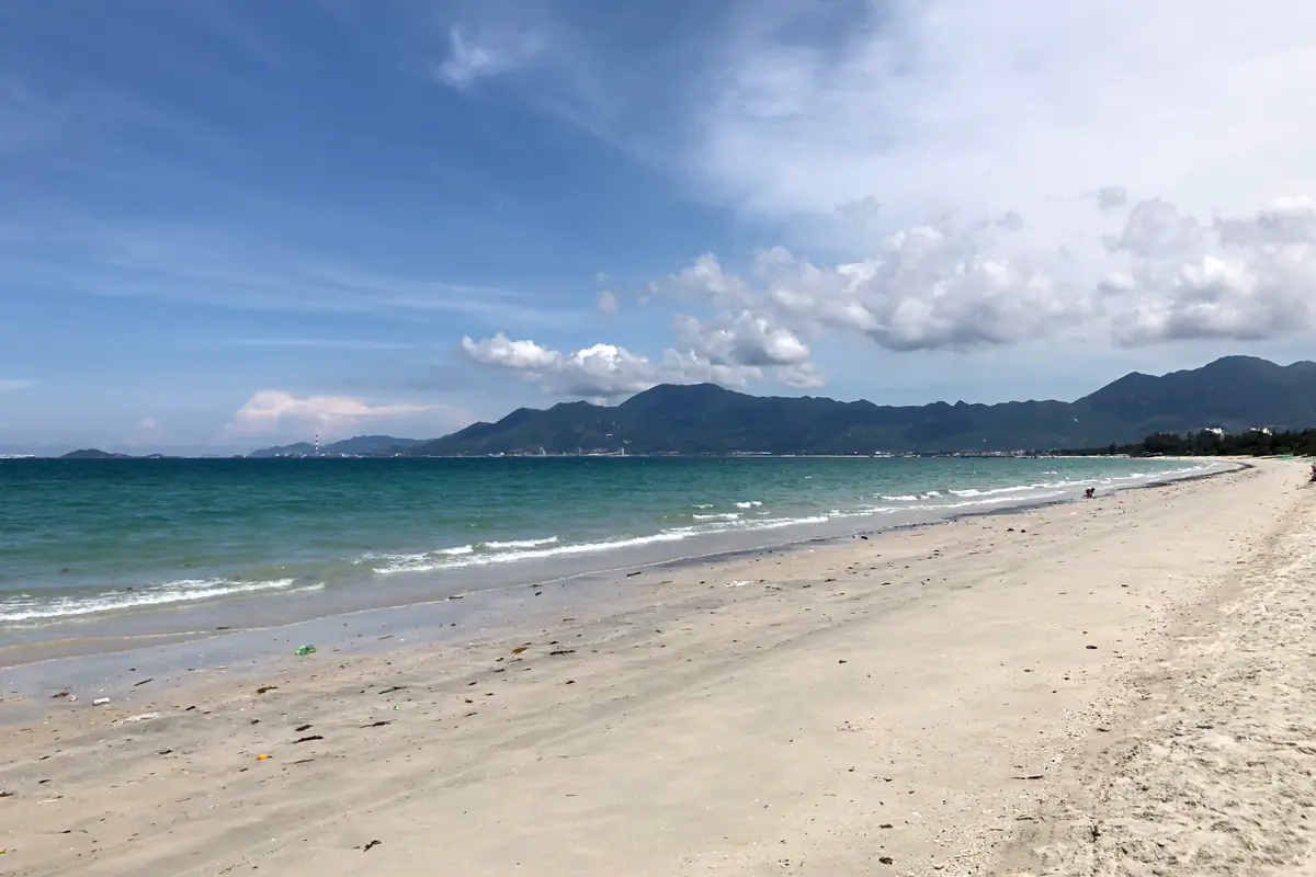 Bãi cát trắng thoải và nước xanh ở Dốc Lết, Ninh Hòa, phía xa là dãy núi bao quanh vịnh, tháng 6/2022