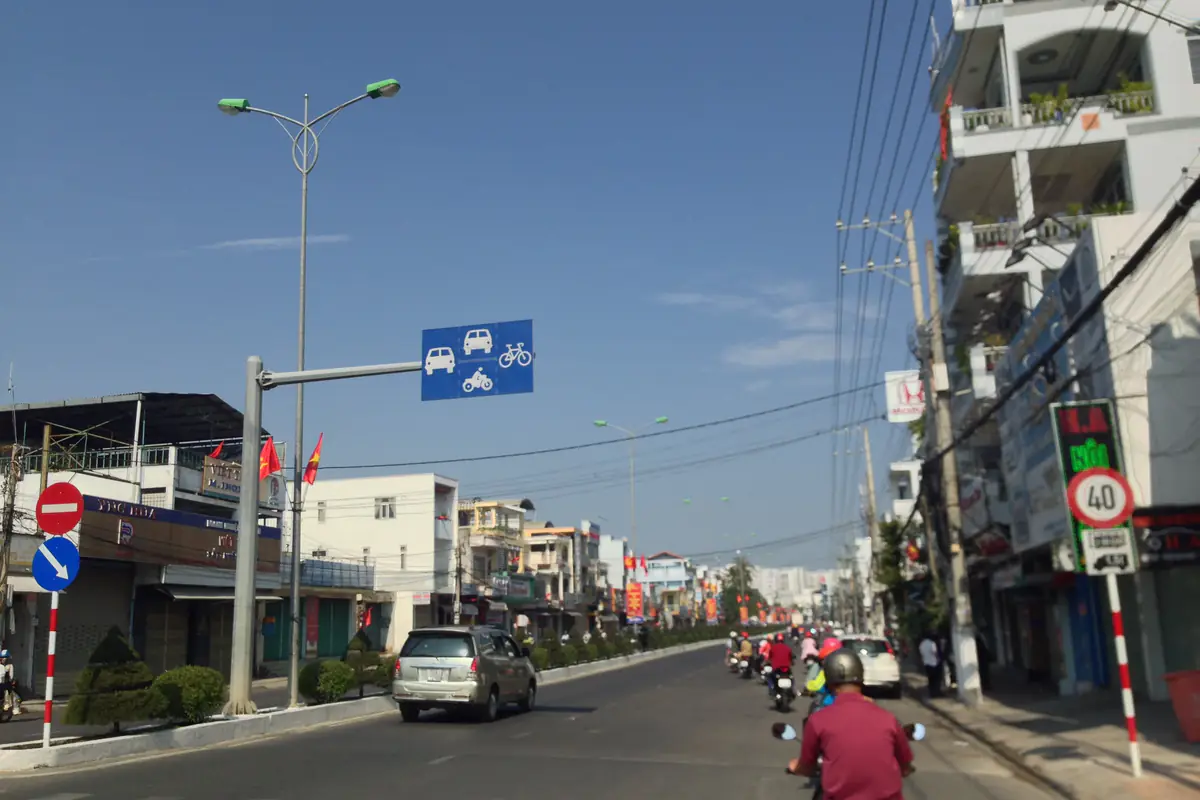 Một tuyến phố ở Nha Trang ngày mùng 1 Tết Mậu Tuất, đường thưa xe, cờ đỏ treo trước nhà, nhiều cửa hàng kéo cửa cuốn, trời nắng xanh, 16/2/2018