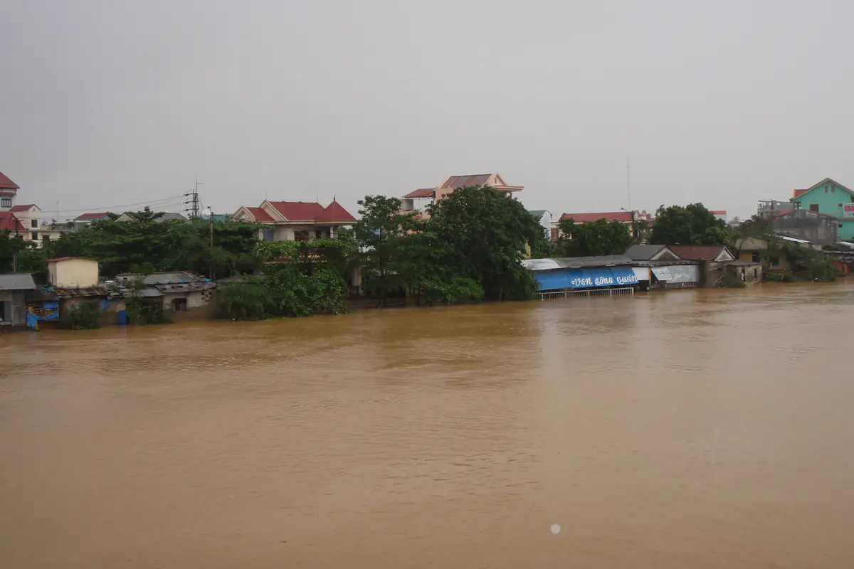 Nước lũ màu nâu dâng ngập bờ sông, tràn tới chân những ngôi nhà ven sông ở Huế dưới trời mưa xám, sau bão Ketsana ngày 30/9/2009