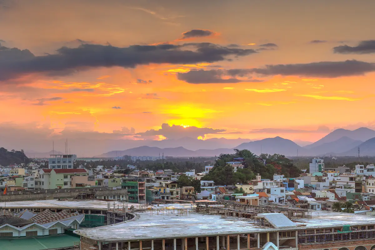 Hoàng hôn nhìn từ khu chợ Đầm, Nha Trang: mặt trời xuống sau dãy núi phía tây, mây chuyển cam đỏ phía trên mái phố, tháng 8/2015