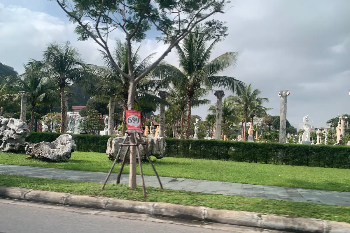 Sân bày tượng và khối đá trang trí dưới hàng dừa ven đường gần chân núi Ngũ Hành Sơn, làng đá Non Nước