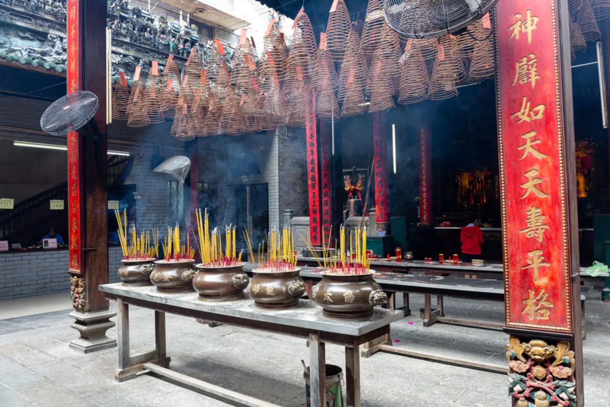 Sân trong chùa Bà Thiên Hậu ở Chợ Lớn, TP.HCM: hàng lư hương cắm nhang trên bàn dài, những vòng nhang xoắn treo dưới mái và câu đối chữ Hán trên cột đỏ, tháng 9/2019
