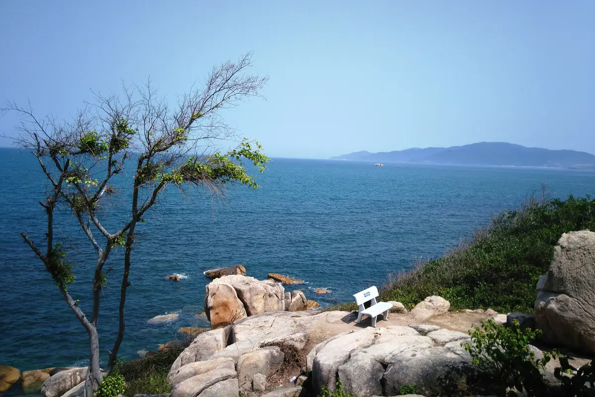 Bãi đá Hòn Chồng ở Nha Trang với chiếc ghế trắng giữa các khối đá granit, phía trước là biển xanh và dãy núi xa, năm 2016