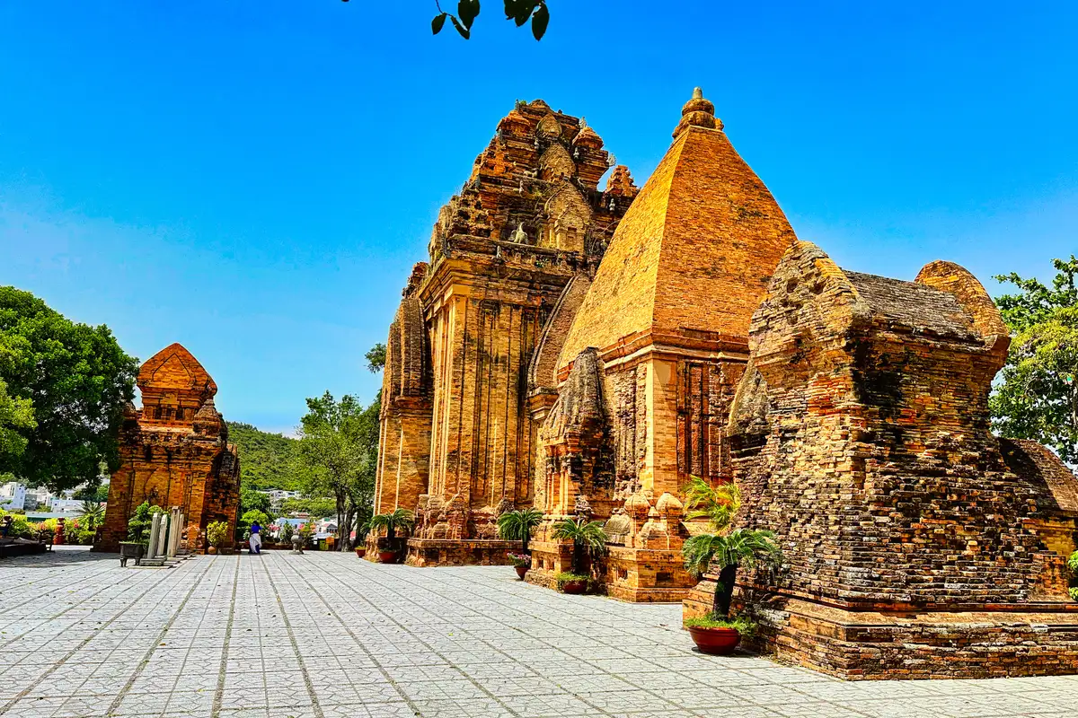 Các tháp gạch Chăm và sân lát gạch của Tháp Bà Ponagar dưới trời xanh, cây xanh hai bên, tháng 4/2023