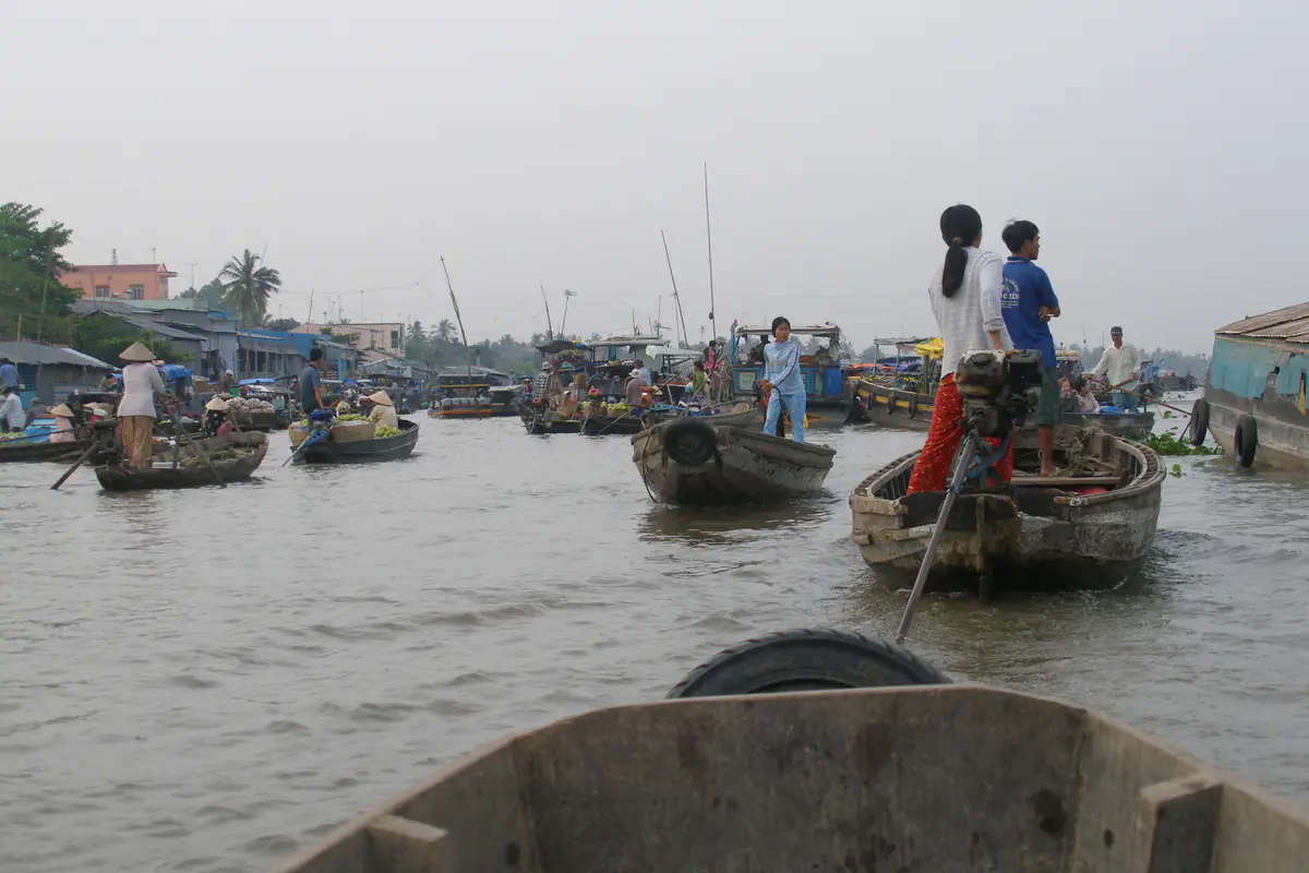 Ghe xuồng chở nông sản trên sông ở chợ nổi Cái Răng, Cần Thơ, lúc sáng sớm giữa tháng 2/2008, người đứng lái ghe, nhà ven sông phía xa