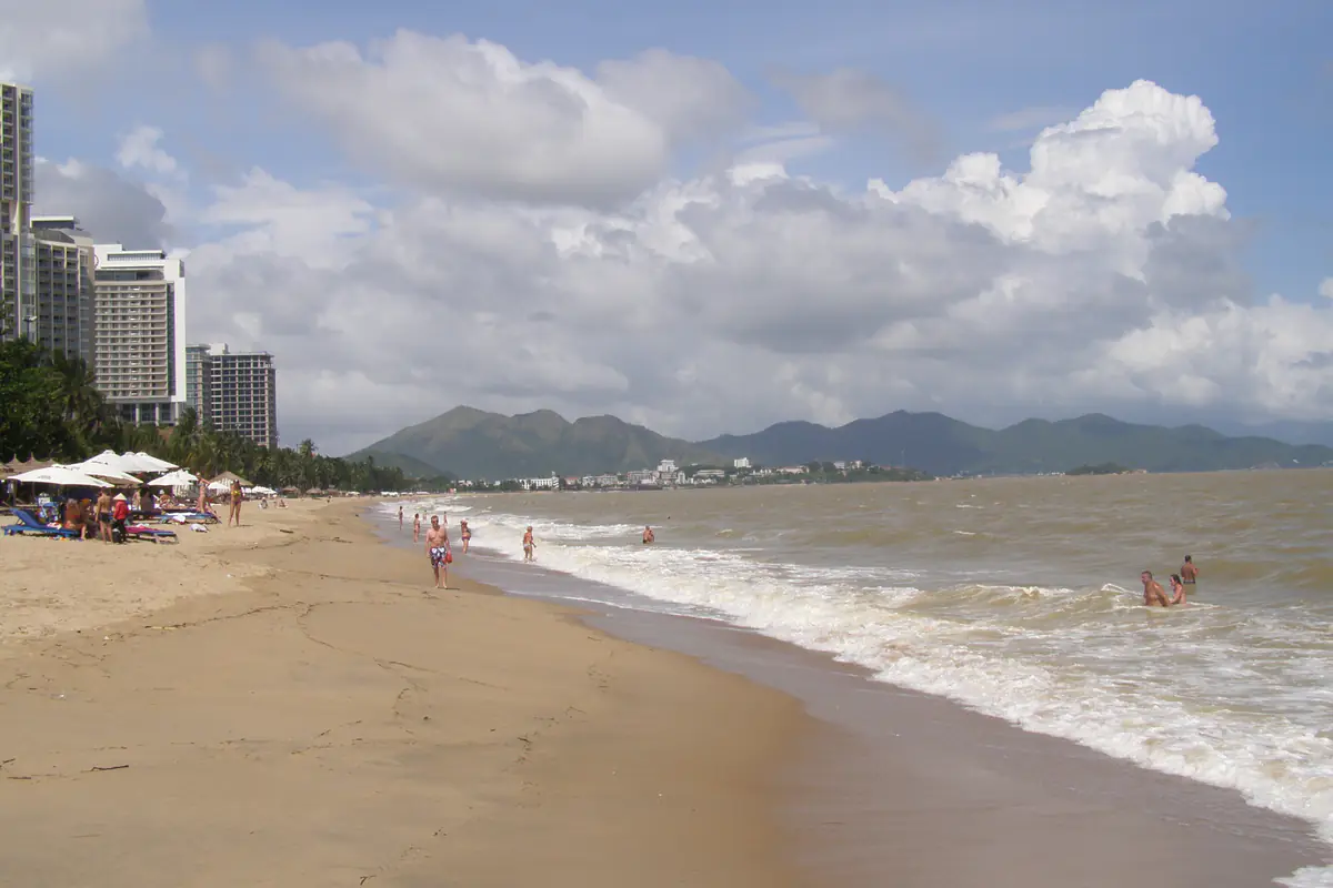 Bãi biển trung tâm Nha Trang một ngày cuối năm: sóng lừng đánh trắng mép nước, khách tắm ở chỗ nông, mây dày phía dãy núi, tháng 11/2013