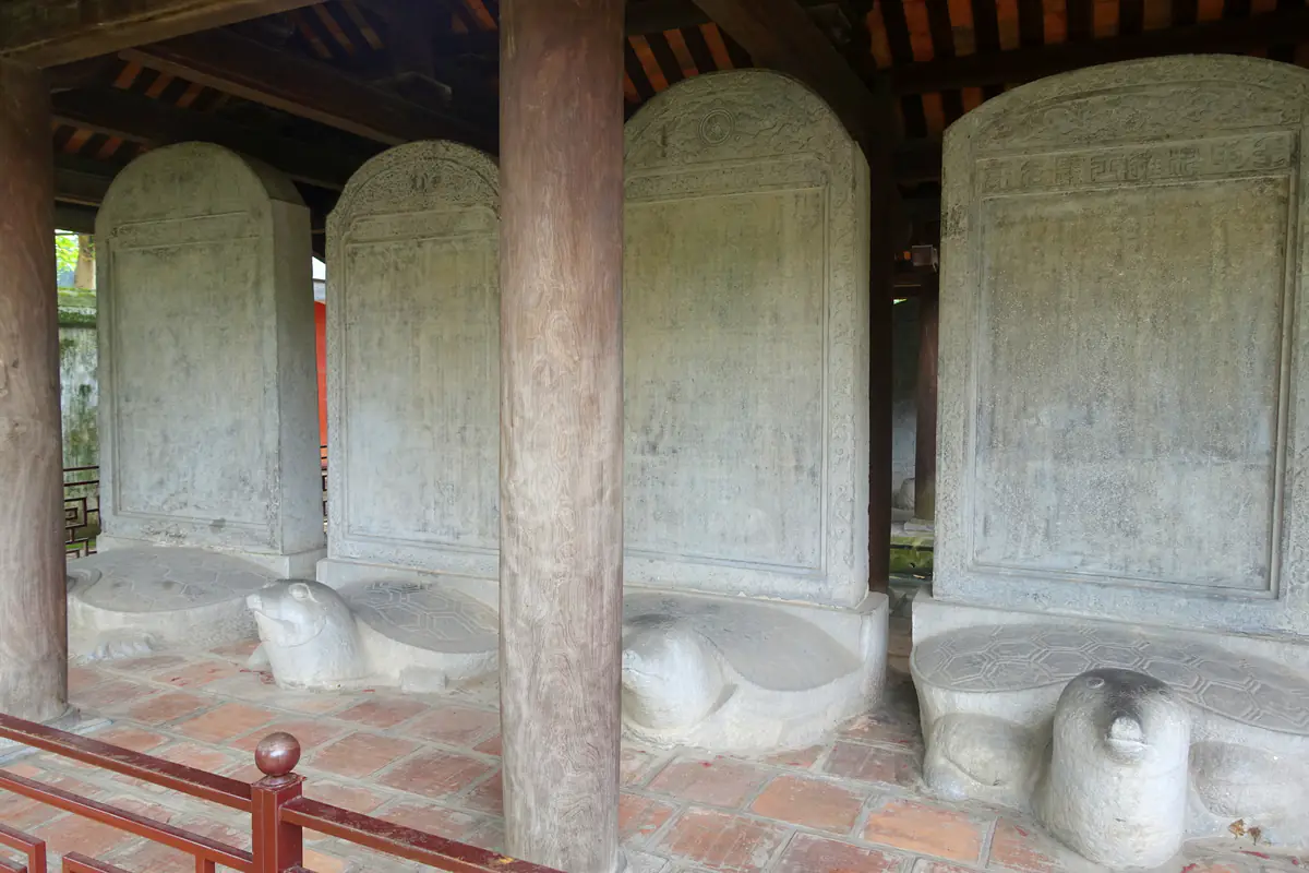 Bốn tấm bia tiến sĩ bằng đá xám đặt trên lưng rùa đá dưới mái nhà bia, phía trước có rào thấp sơn đỏ, Văn Miếu - Quốc Tử Giám, tháng 8/2014
